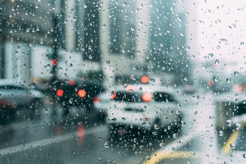 雨でぬれたガラスごしに見える車